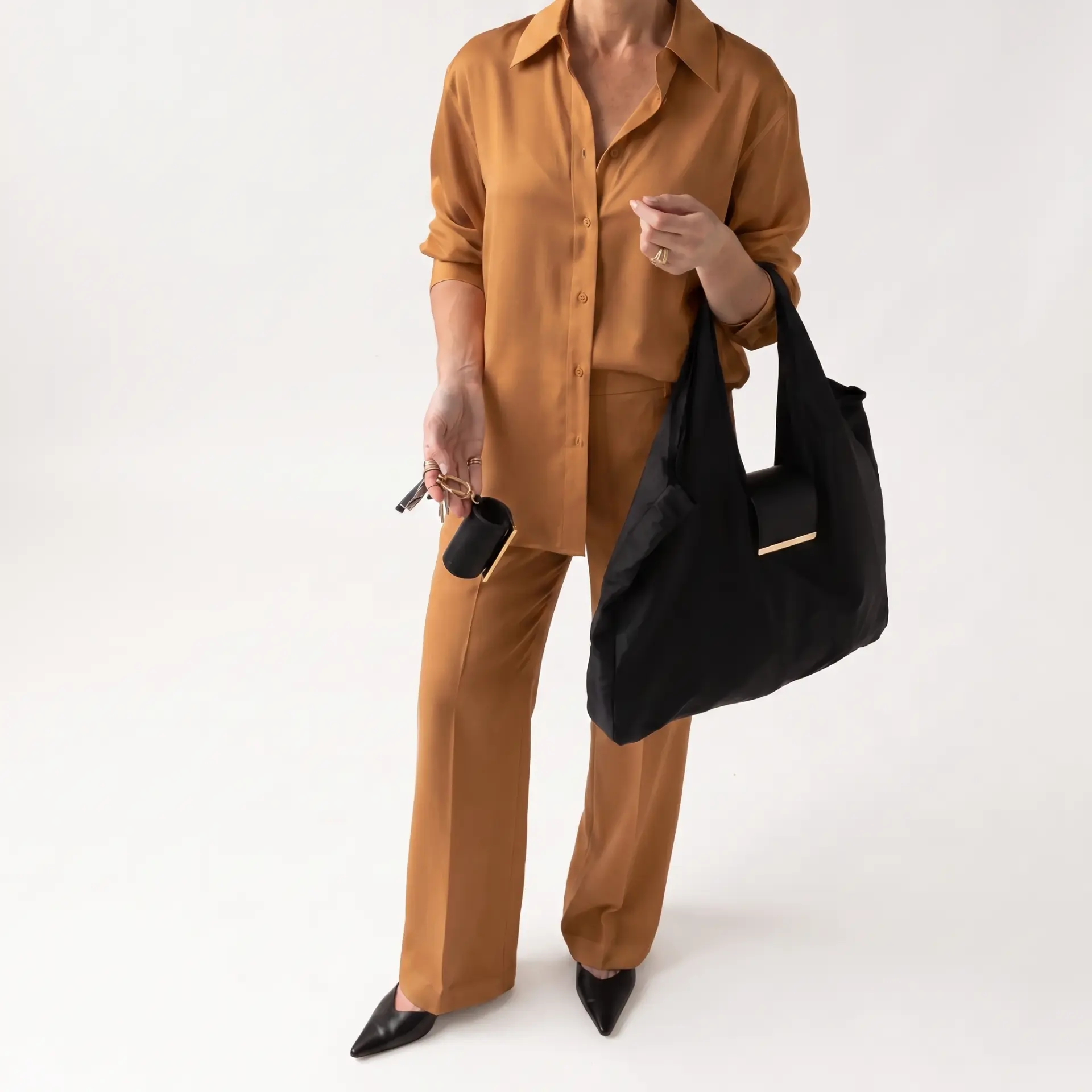 Model in a tan silk suit carrying the black Cliqué Tote with the pouch on her keys