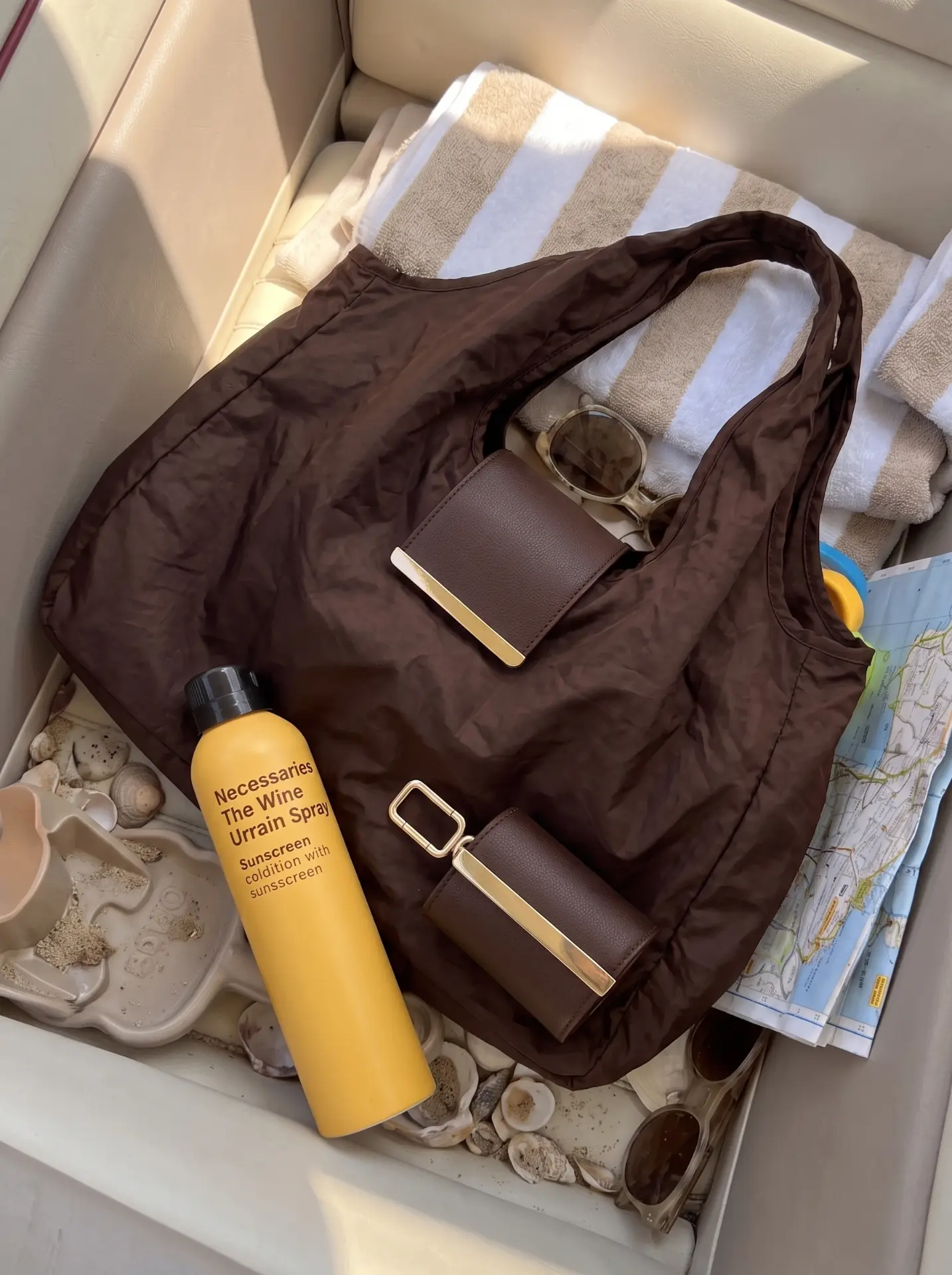 Cocoa Cliqué Tote packed with a towel, sunscreen and sunglasses in the back of a car