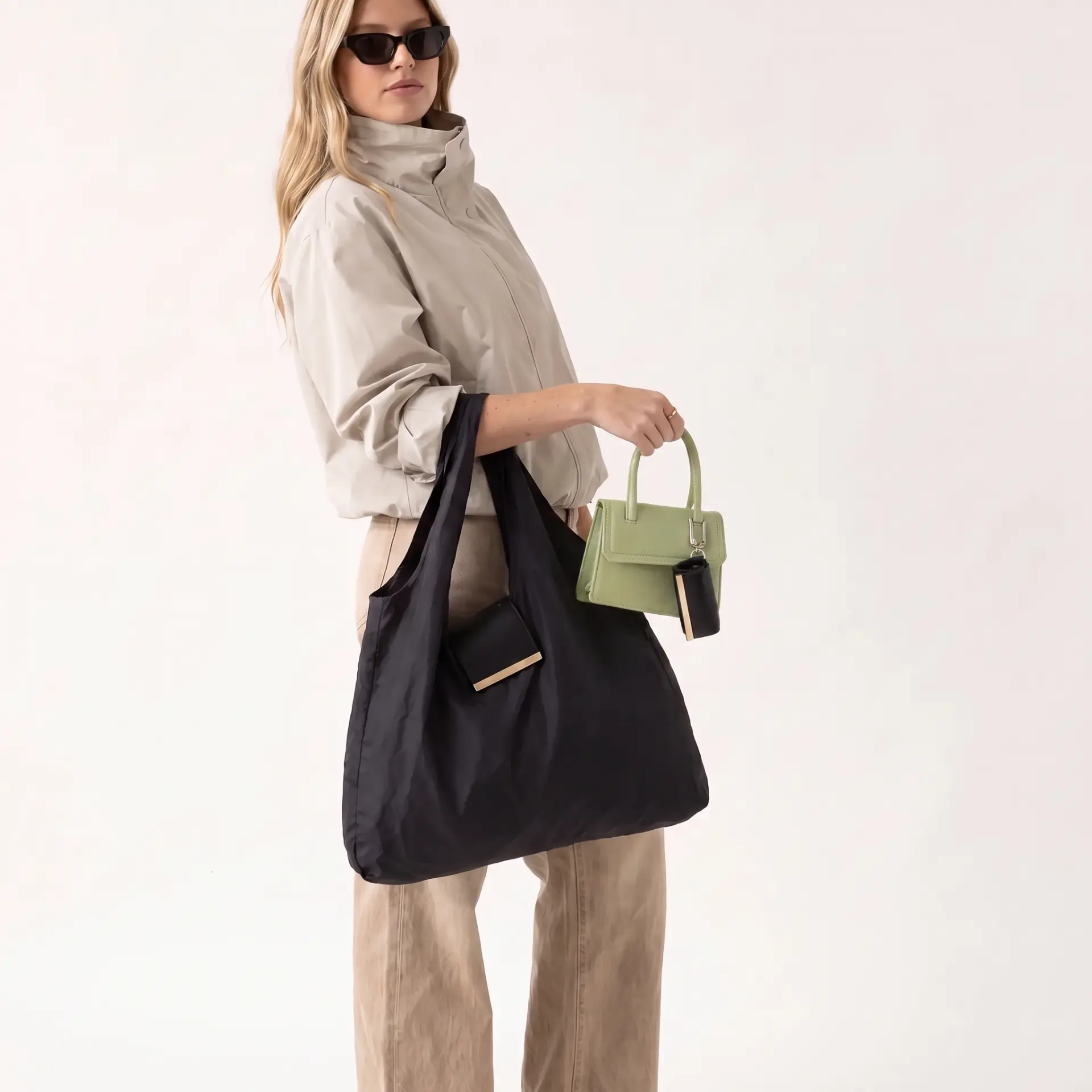 Model carrying the black Cliqué Tote on her shoulder with a green mini bag